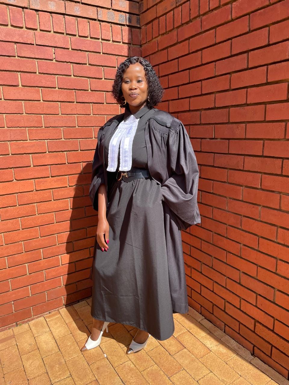 Ms Mogotlane standing outside in a full black court robe with white legal bands