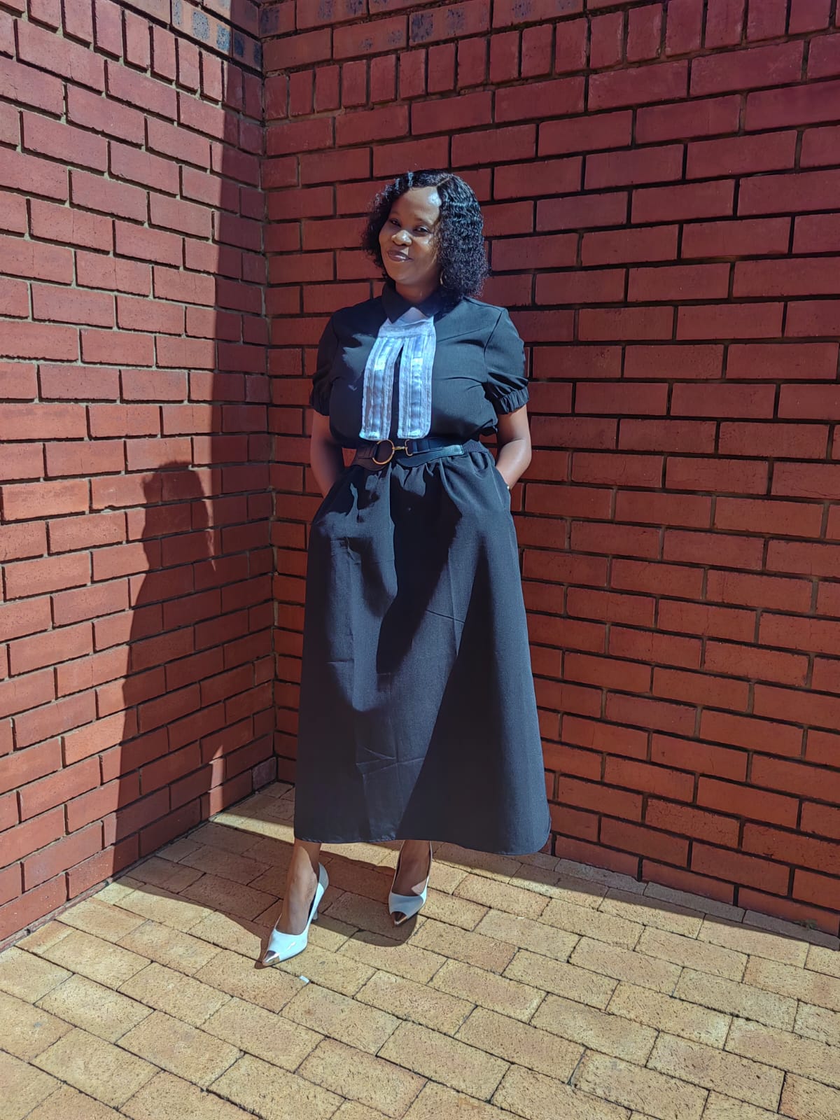 Ms Mogotlane outside the court building in a black dress with her legal bands
